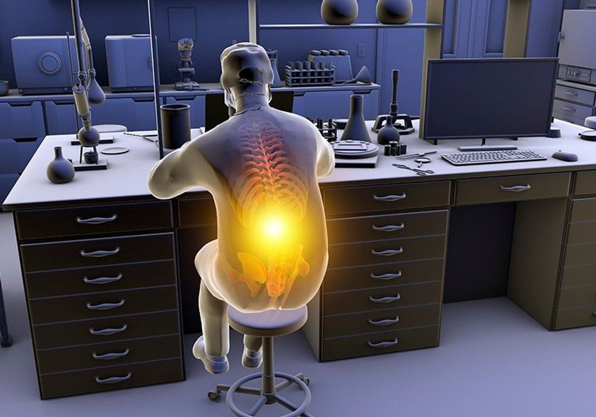 A person slouches while sitting at their laboratory bench, causing musculoskeletal strain, indicated by a yellow highlight on their spine. A person slouches while sitting at their laboratory bench, causing musculoskeletal strain, indicated by a yellow highlight on their spine.