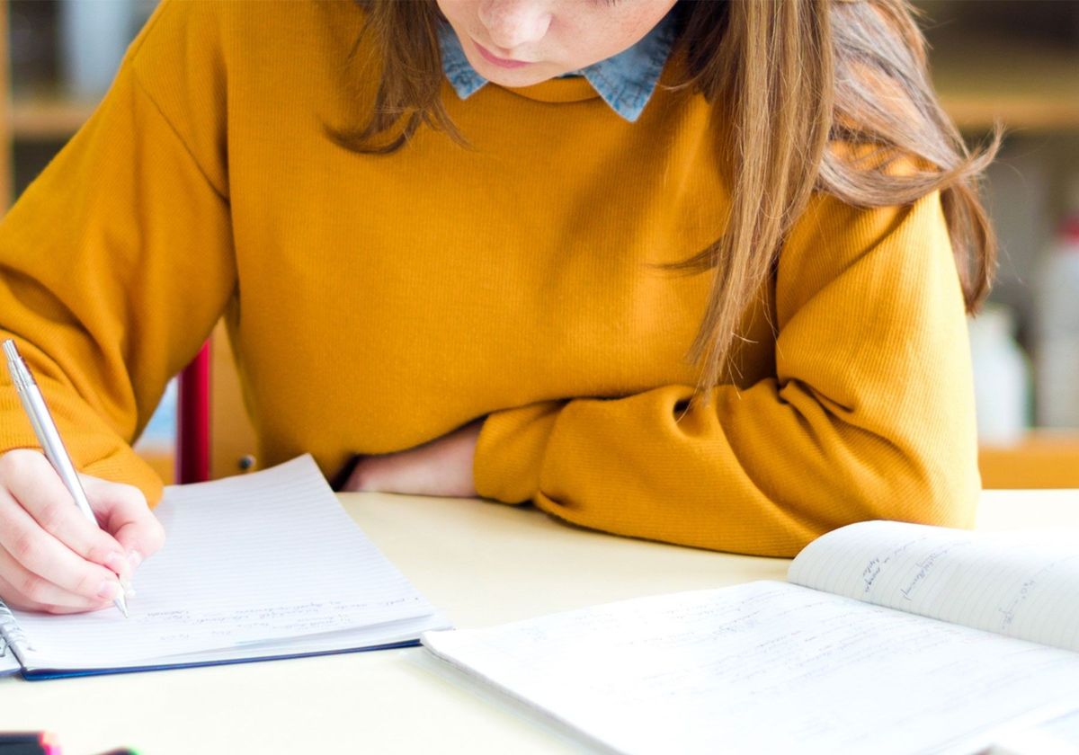 A person sitting in a laboratory writing notes with a pen in a notebook. A person sitting in a laboratory writing notes with a pen in a notebook.