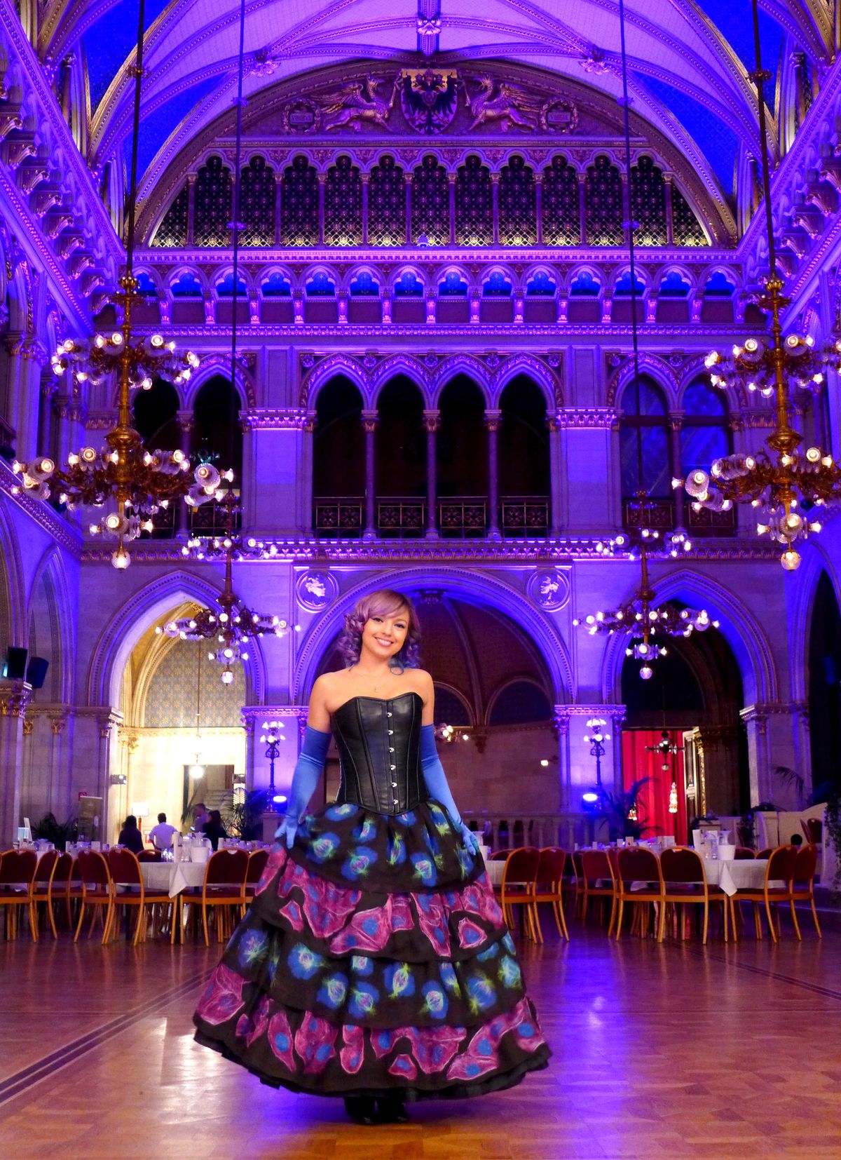 Beata Mierzwa stands in a ballroom wearing a dress for a fashion show. Her skirt contains images of fluorescently-labeled cells that she imaged on a microscope and printed onto the fabric. Beata Mierzwa stands in a ballroom wearing a dress for a fashion show. Her skirt contains images of fluorescently-labeled cells that she imaged on a microscope and printed onto the fabric.