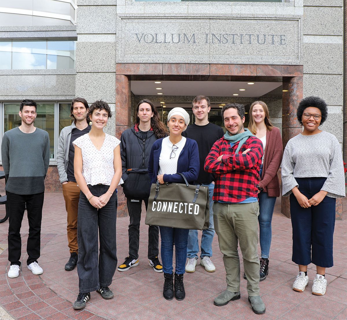 A group of researchers stand outside a building labelled the Vollum Institute. A group of researchers stand outside a building labelled the Vollum Institute.