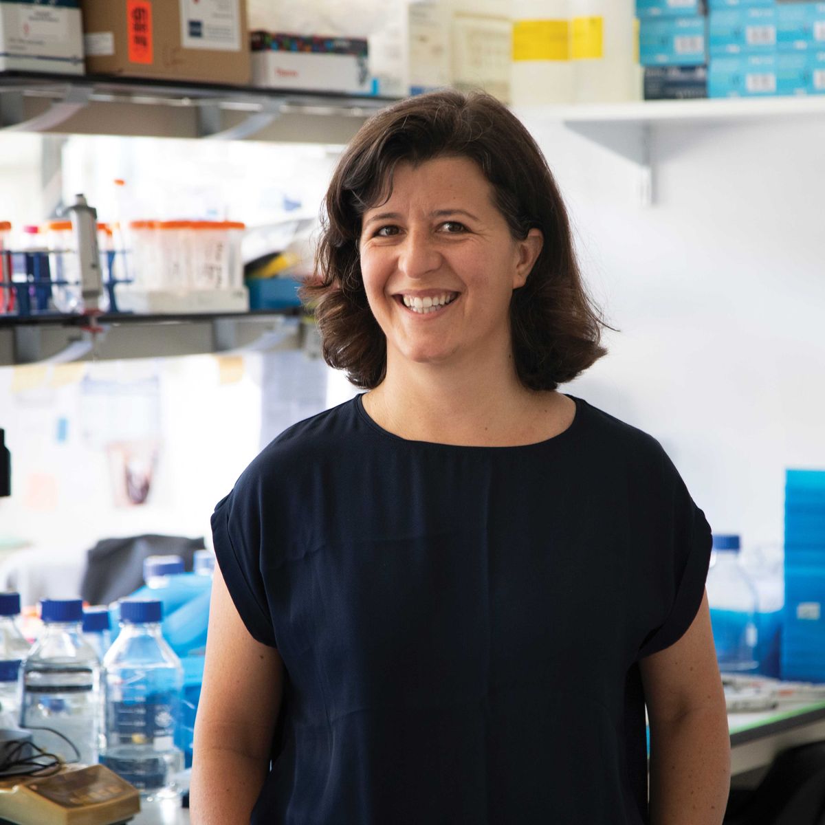 A woman is in a research laboratory. She wears a black shirt and smiles. A woman is in a research laboratory. She wears a black shirt and smiles.