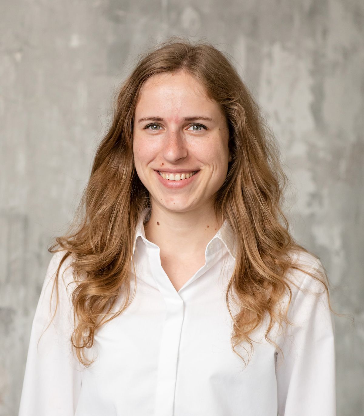 Sophie Farkas wears a white button-down and smiles against a grey backdrop. Sophie Farkas wears a white button-down and smiles against a grey backdrop.