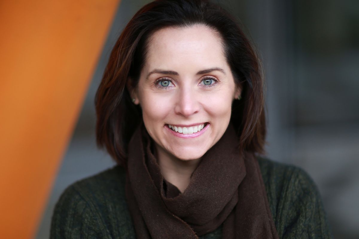A young woman wears a dark green pullover and a winter scarf. She looks at the camera and smiles. A young woman wears a dark green pullover and a winter scarf. She looks at the camera and smiles.