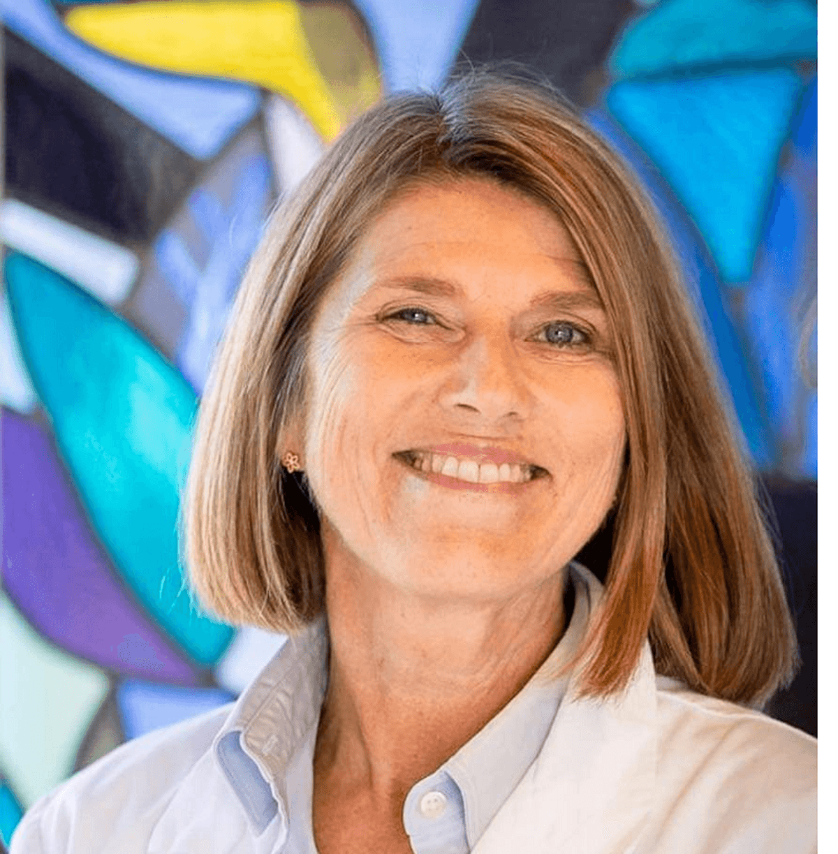 Anne Cathrine Staff wears a collared shirt and smiles against a multicolored background. Anne Cathrine Staff wears a collared shirt and smiles against a multicolored background.